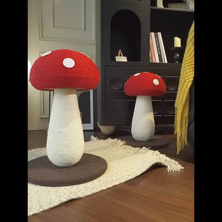 Two mushroom-shaped cat trees on a wooden floor with a bookshelf in the background.