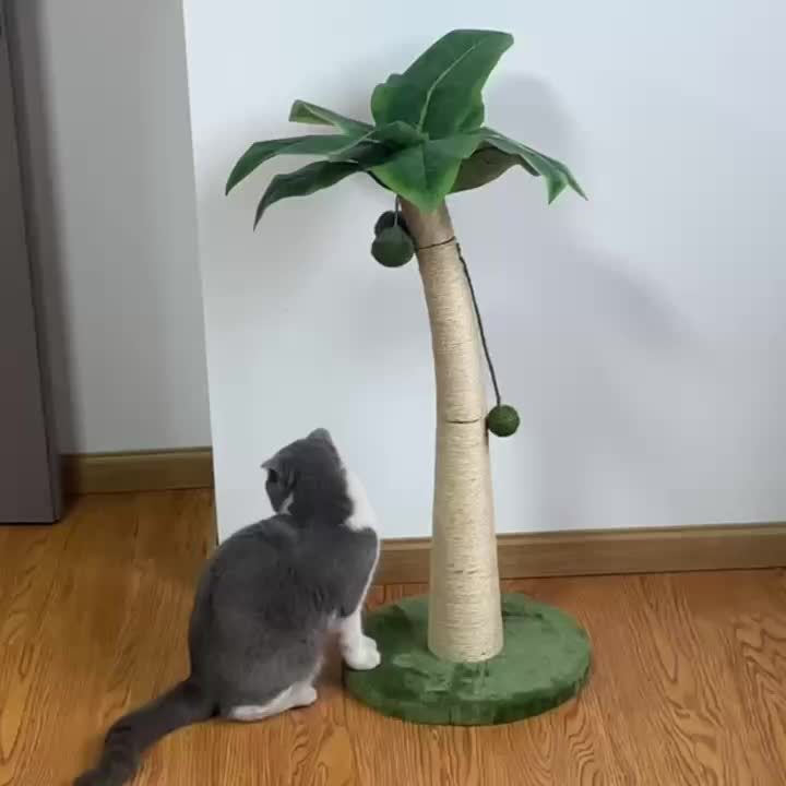 Cat playing with a cat tree designed like a palm tree on a wooden floor.