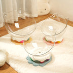 Three cat-shaped glass beds on stands with colorful bases on a white rug.