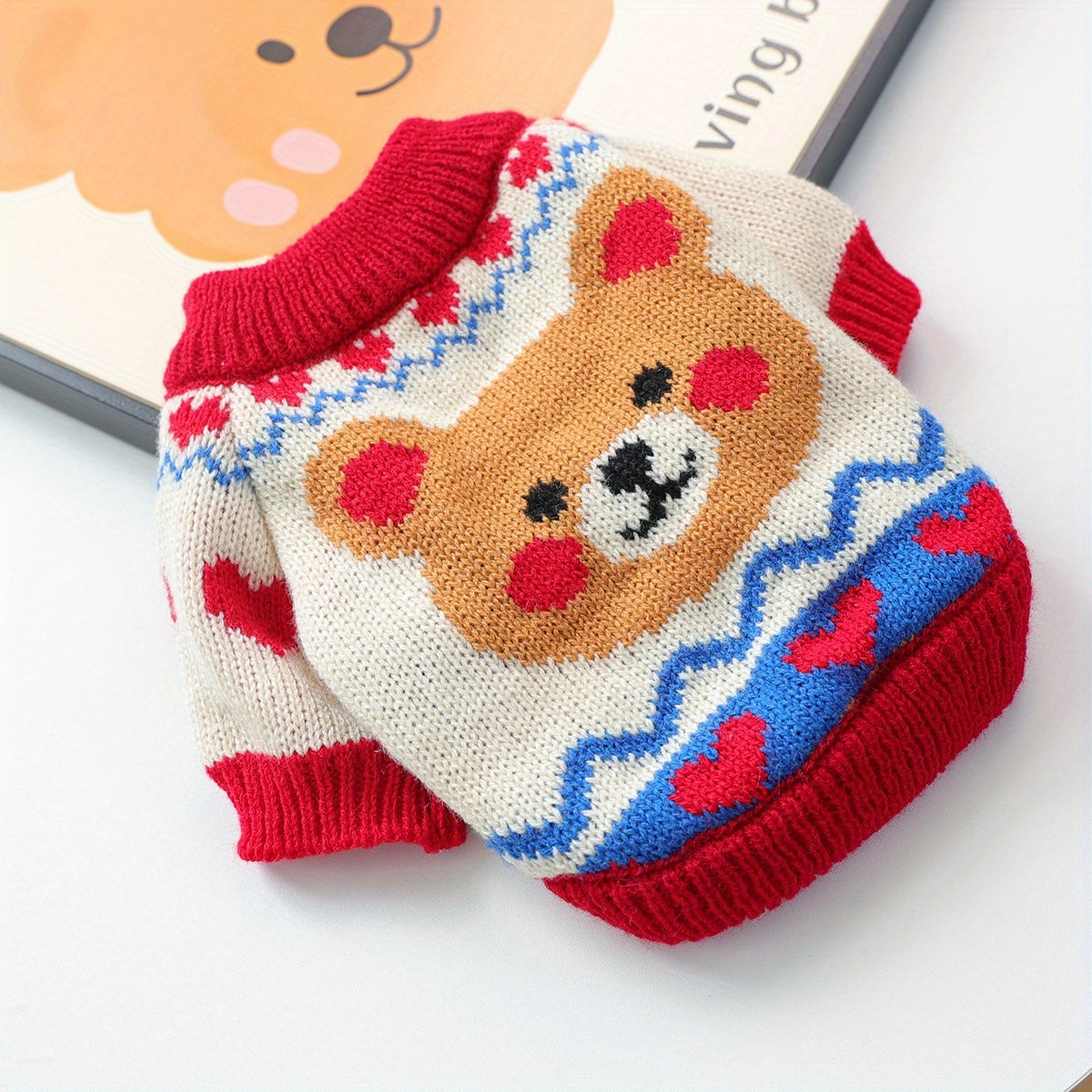 Cartoon bear sweater with red collar and heart patterns on a white background