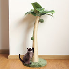 Cat climbing a palm tree-shaped cat toy on a wooden floor.