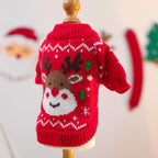 Red knitted sweater with reindeer design on a mannequin against a festive background.