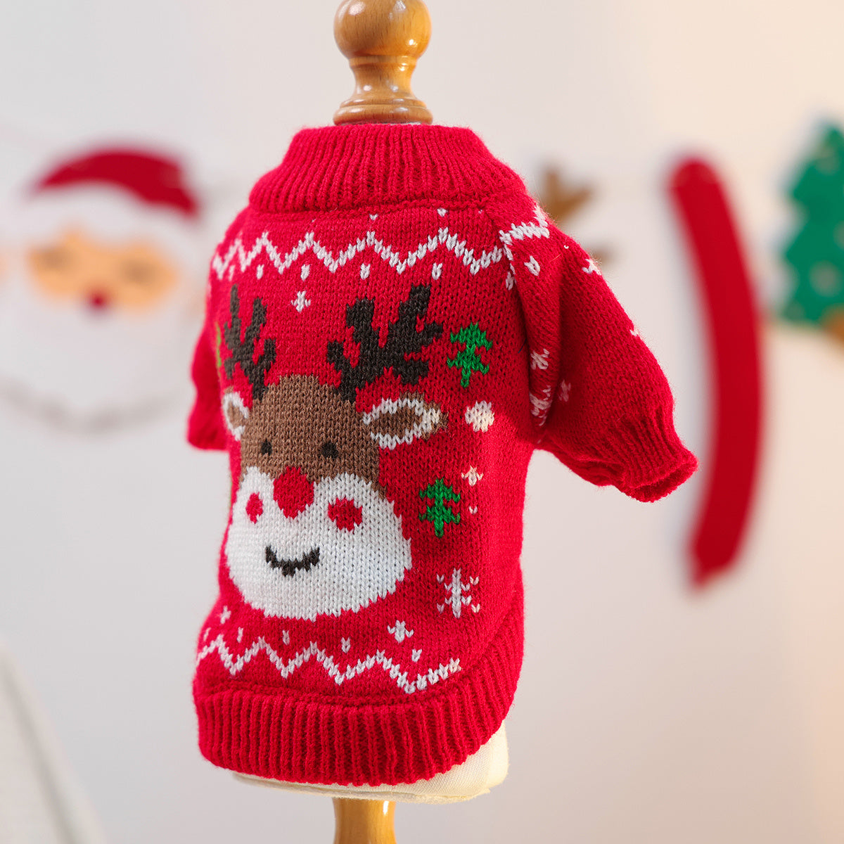 Red knitted sweater with reindeer design on a mannequin against a festive background.