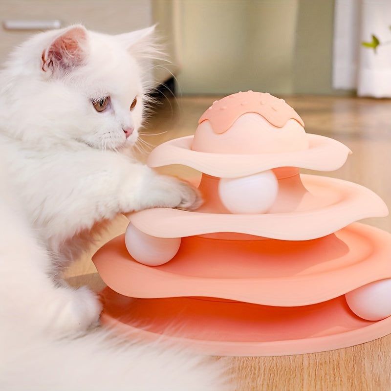 White cat playing with a pink and white cat toy on a wooden floor.