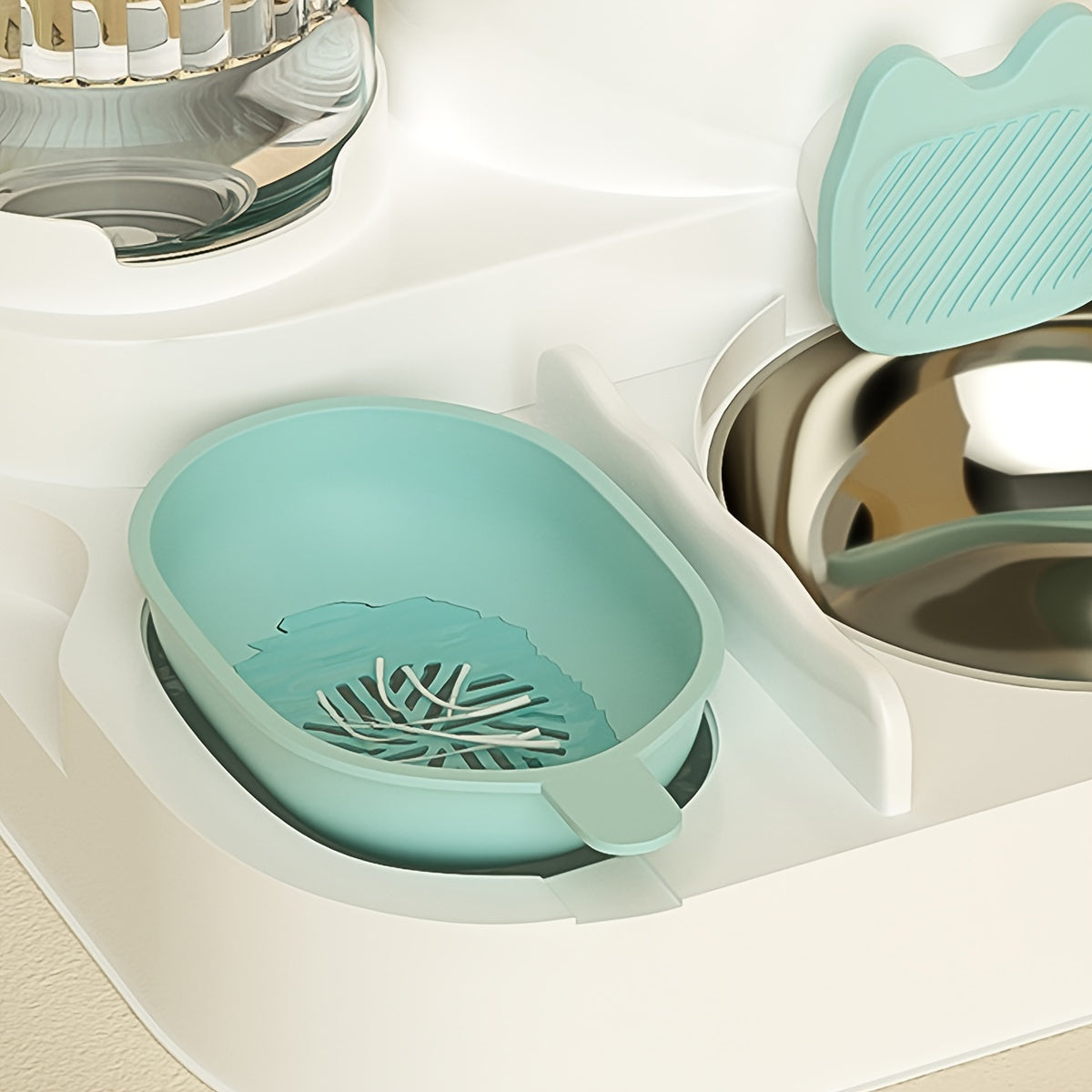 Teal pet bowl with a leaf design on a white surface