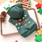 Green hoodie with Christmas lights design on a wooden tray with decorative items.
