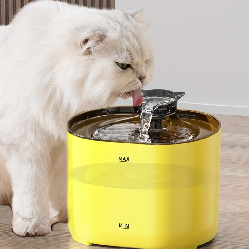 White cat drinking water from a yellow pet fountain on a wooden floor.