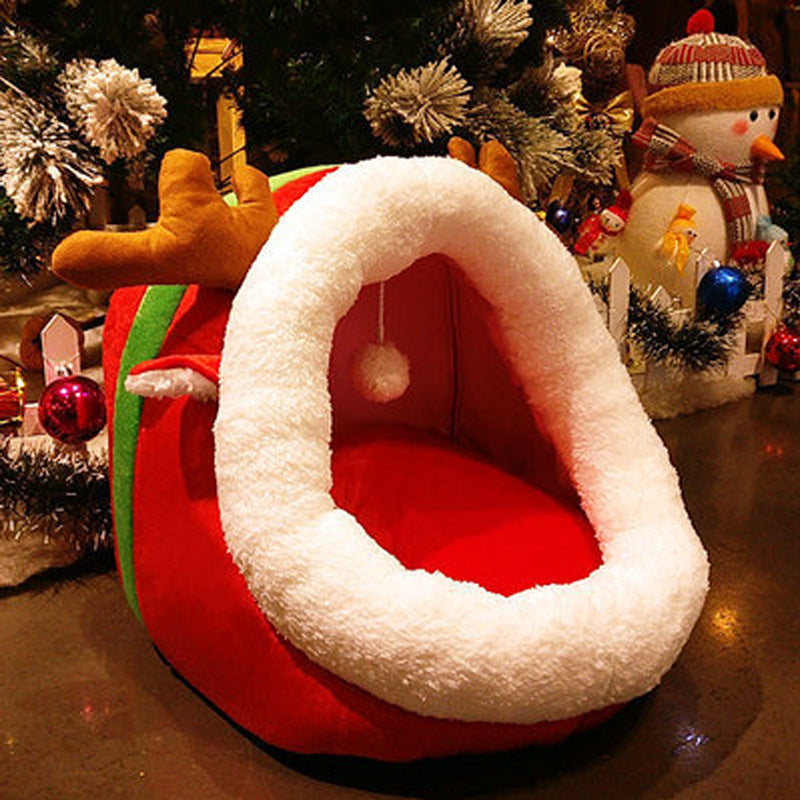 Red and white pet bed shaped like a sleigh with Christmas decorations in the background.