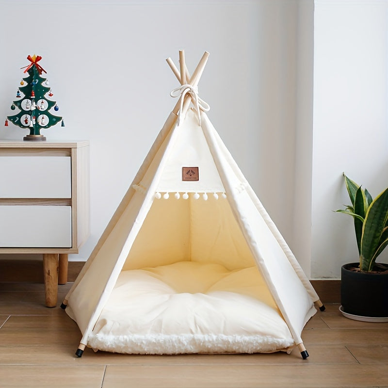 White pet teepee with a soft interior on a wooden floor, next to a small Christmas tree and plant.