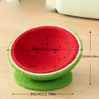 Red and green pet bed shaped like a watermelon with measurements on a wooden floor.