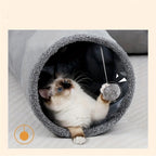 Cat playing with a toy inside a gray pet cave on a light background