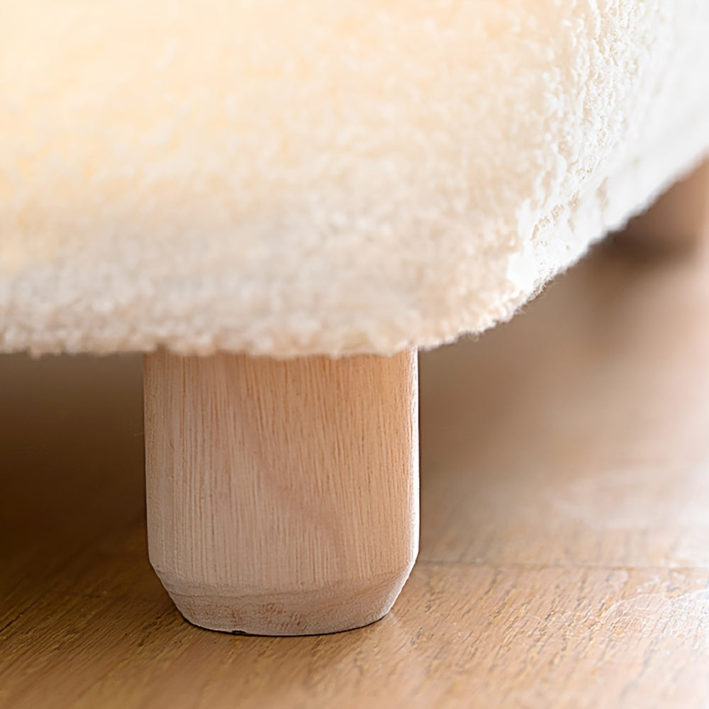 Close-up of a soft, plush cushion with a wooden base on a wooden floor.
