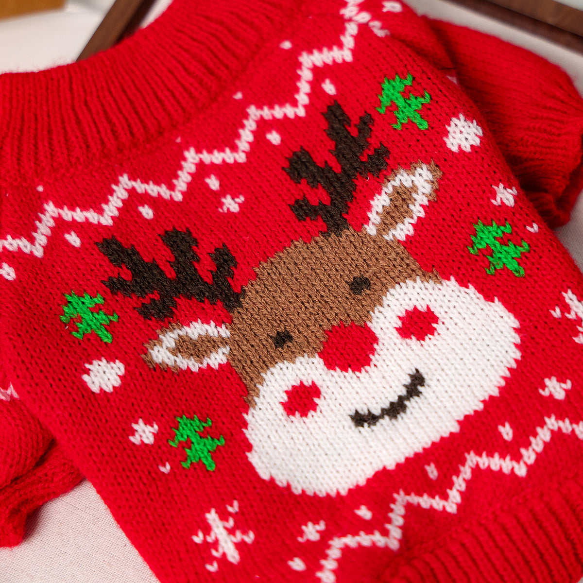 Red knitted sweater with a reindeer design on a white background