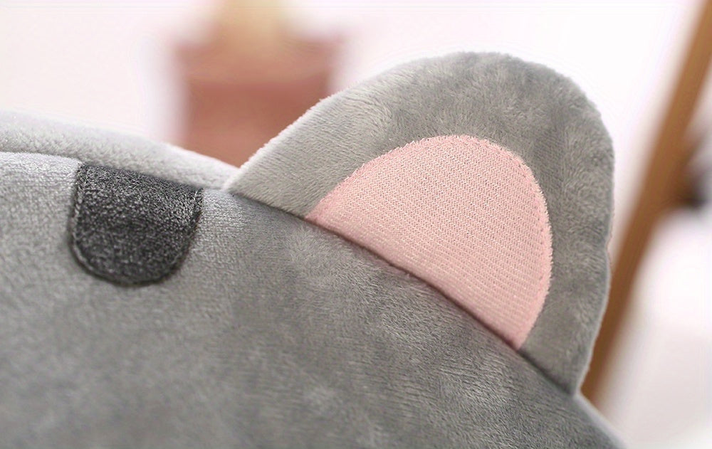 Gray plush toy with pink heart detail on a blurred background
