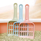 Three colorful cat litter scoops on a bed of cat litter with a neutral background.