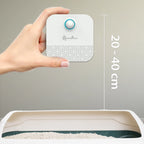 Hand holding a small white device with measurement details on a gray background