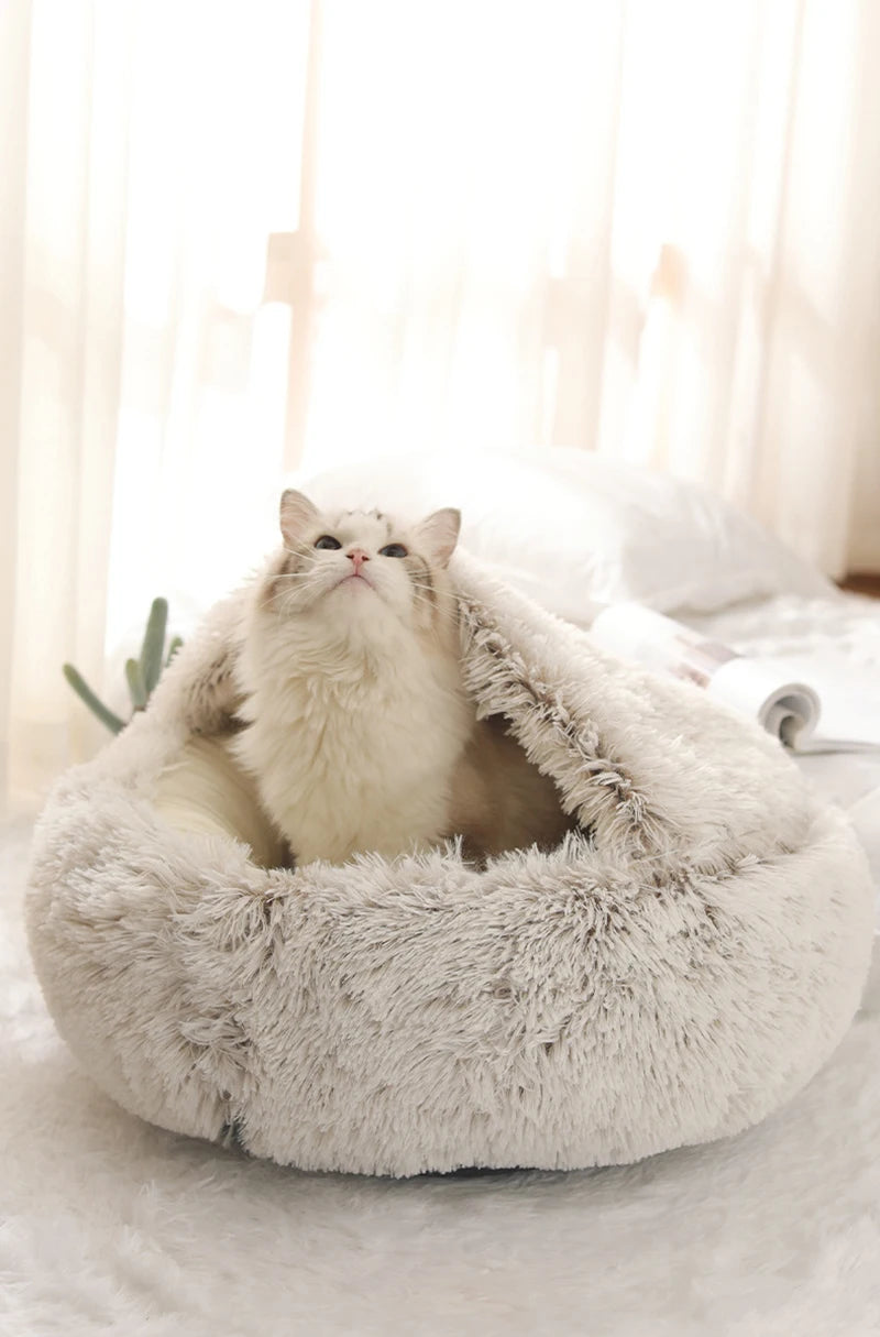 Cat sitting inside a fluffy beige pet bed with a soft white background