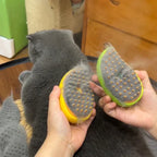 Person holding two grooming tools with pet hair on them next to a gray cat.