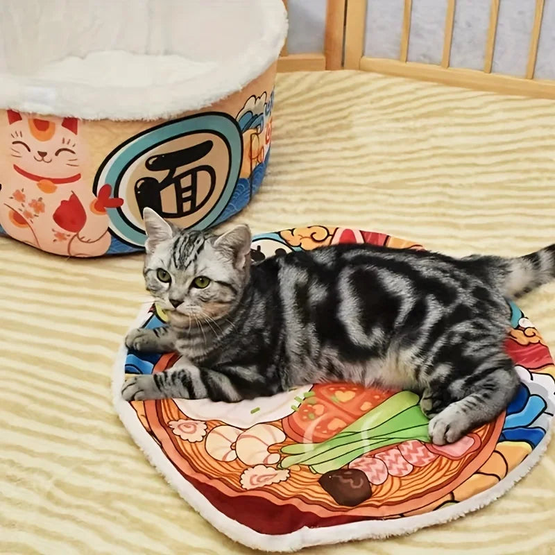 Cat lying on a colorful mat with a noodle design, next to a cat bed with cartoon face.
