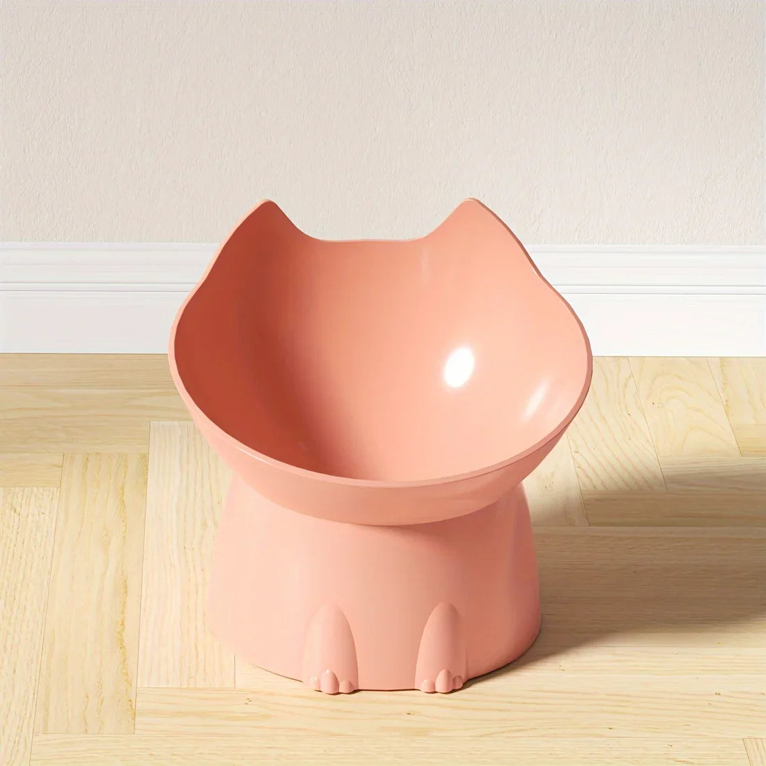 Pink cat-shaped bowl on a wooden floor with a light-colored wall background