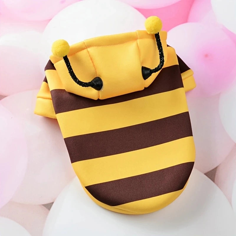 Yellow and brown striped pouch with pom-pom details on a pink and white background