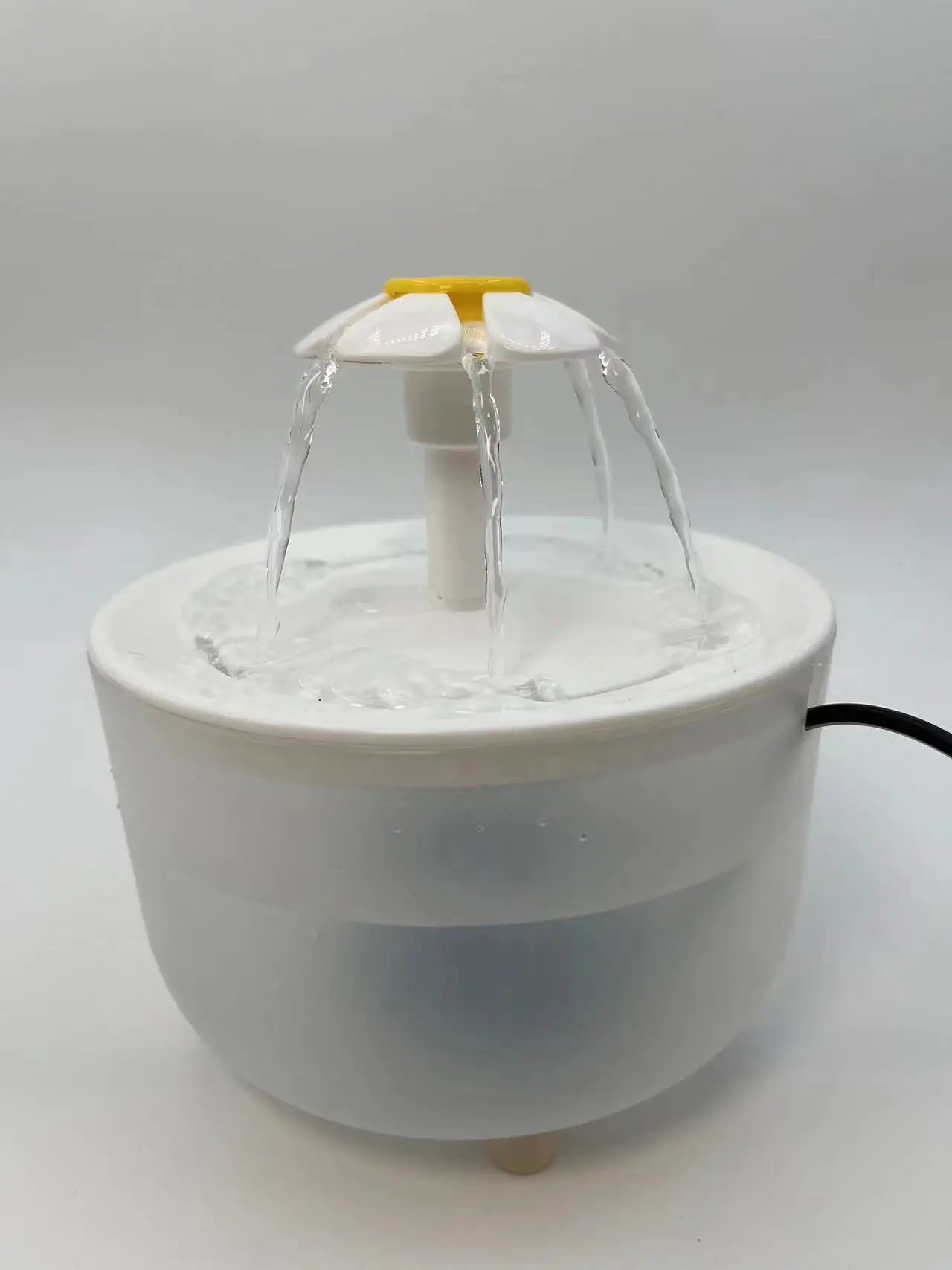 Small white water fountain with a yellow top on a light gray background