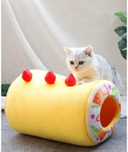 Cat lying inside a yellow fruit-themed pet bed with red berries on a light background