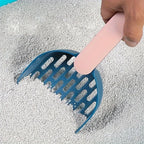 Blue scoop being used to gather cat litter on a gray surface