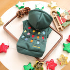 Green pet hoodie with Christmas lights design on a white surface with festive decorations.