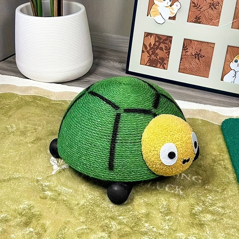 Green turtle-shaped cat's scratcher on a textured surface with a plant and framed pictures in the background.