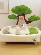 Cat lying on a pet bed with a tree-shaped toy in the background