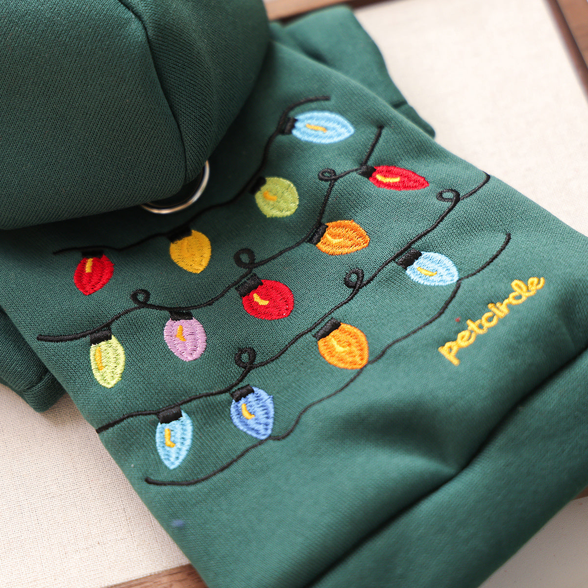 Green fabric with embroidered colorful lights and 'Petcircle' branding.