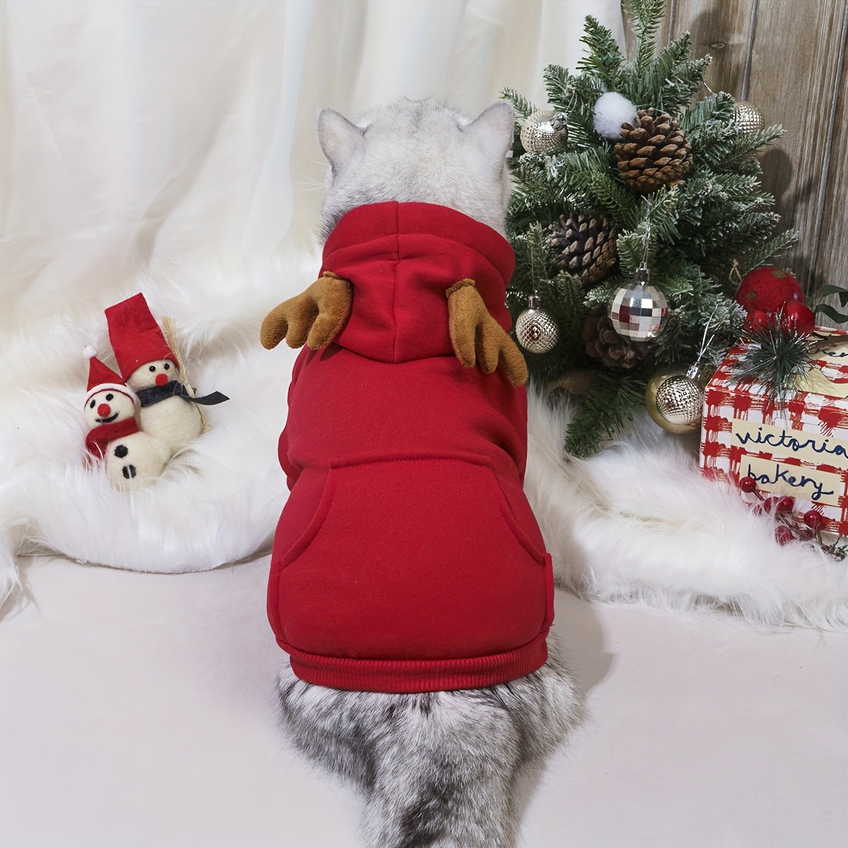 Dog wearing a red hoodie with Christmas decorations in the background