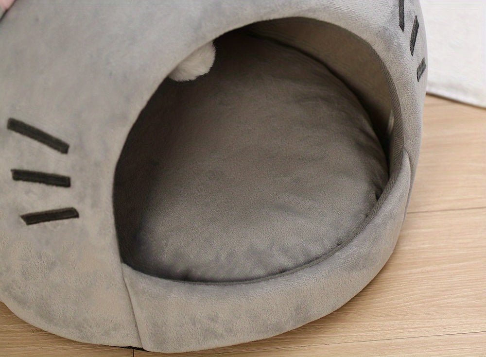 Gray pet bed shaped like a cat's face on a wooden floor