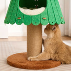 Cat playing with a green tree-shaped cat tree on a wooden floor.