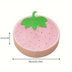 Pink strawberry-shaped cushion with green leaf on a white background