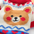 Close-up of a knitted sweater with a bear design and red hearts on a white background