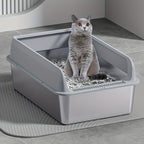 Cat sitting inside a gray litter box on a tiled floor.