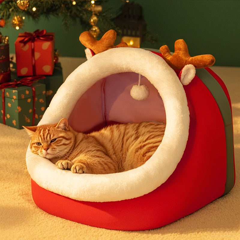 Cat lying in a red pet bed with reindeer antlers near Christmas presents.